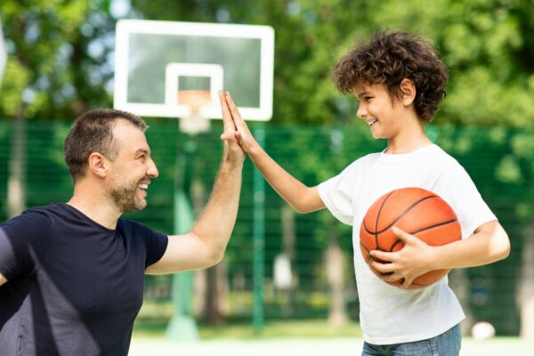 Portrait of man and boy giving high five playing basketball