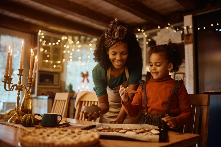 Happy black mother and daughter enjoying in making holiday cookies in the kitchen.